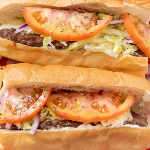 Two Giovanni's Pizza subs, filled with meat, lettuce, onions, tomatoes, and sauce.