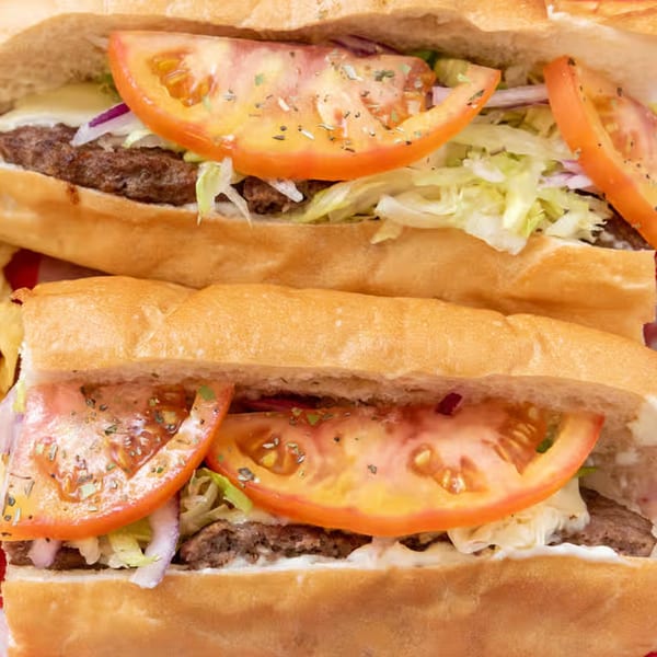 Two Giovanni's Pizza subs filled with meat, cheese, lettuce, onions, and tomatoes.
